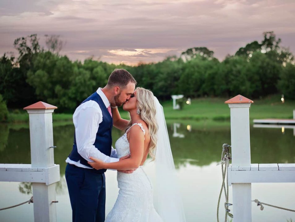 A bride and groom kiss on the pond dock at sunset, one of a dozen outdoor ceremony sites at this New Market farm wedding venue