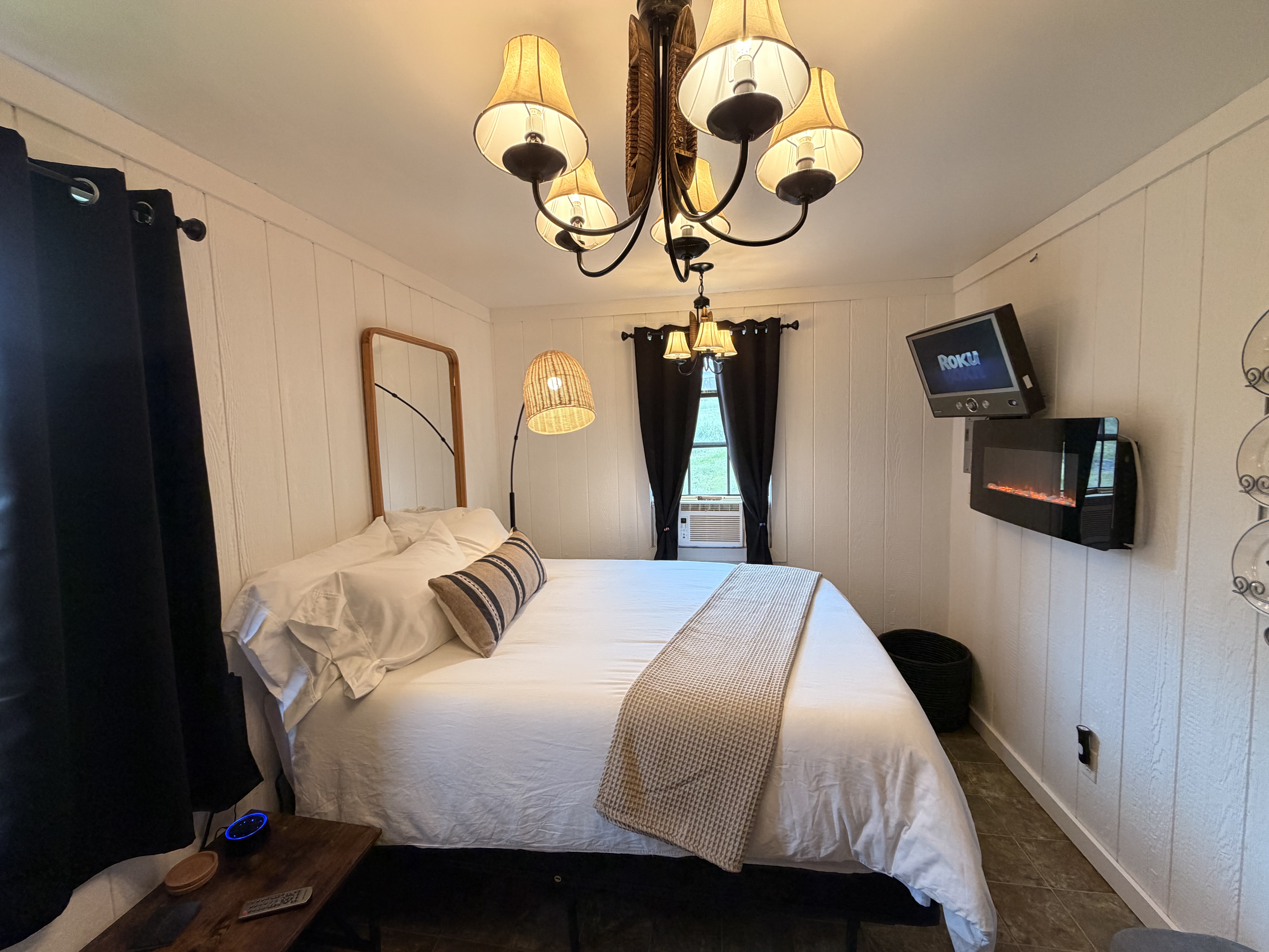 Cozy queen bedroom with fireplace, TV, and warm designer lighting